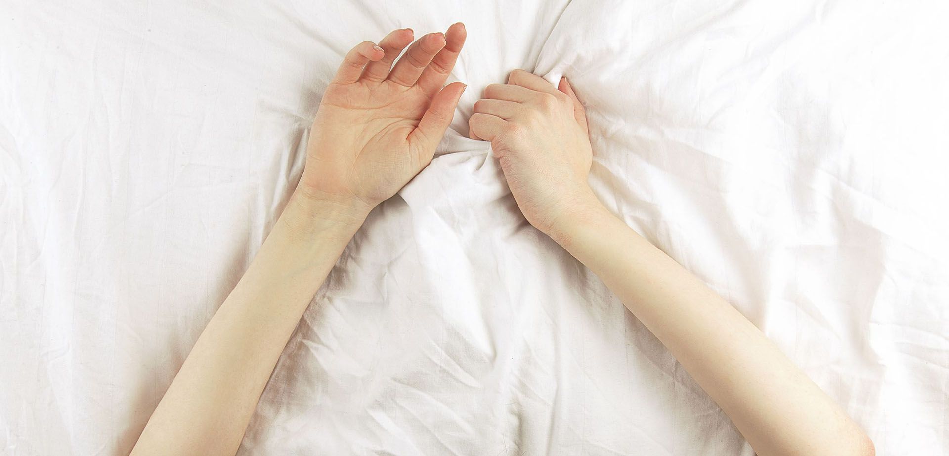 Female hands on the bed.